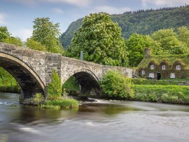 An elegant 17th century stone bridge over the River Conwy at Llanrwst, with the ivy-clad Tu Hwnt ir Bont National Trust tearooms on the western side. The bridge was built in 1636